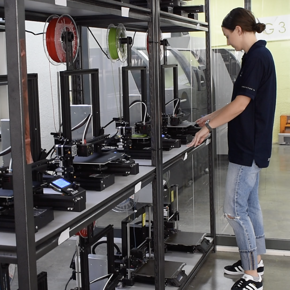 Worker standing in front of multiple 3D printing machines